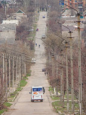 Dar, asfaltsız bir yol, bitki örtüsü, elektrik direkleri ve teslimat kamyonu. İnsanlar kapalı bir gökyüzünde, Kostiantynivka, Ukrayna, 01-15-2013 'e sessiz toprakla görülebiliyor.