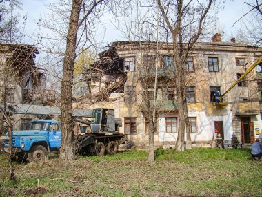 Görüntü, doğal afet veya çatışma gibi bir olay sonrasında kentin yıkılışını gösteriyor. Mavi kazıcıyla temizlik yapan iki kişi Ukrayna, Kostiantynivka, 01-15-2013