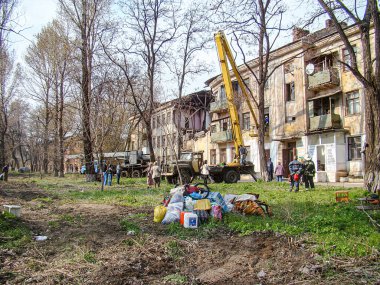 Şehir yıkım sahnesinde enkaz, ağır makineler ve yıkık dökük işçiler bölgeyi bulutlu bir gökyüzü ile çevreleyen genel hava durumu desol Kostiantynivka, Ukrayna, 01-15-2013