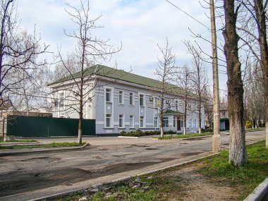 İki katlı, pencereleri, balkon verandaları ve bacası olan beyaz bir apartman. Arazinin garaj ya da avlusu var, yaprakları olmayan ağaçlar, Kostiantynivka, Ukrayna, 01-15-2013