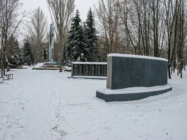 Açık hava kış anıtı, büyük taştan bir plaket, karla kaplı basamaklar, bulutlu gökyüzü ve çevreleyen çıplak ağaçlar Kostiantynivka, Ukrayna, 01-15-2013
