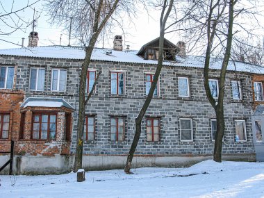 Karla kaplı, gri tuğlalı, daha soğuk bir iklim bölgesinde koyu ahşap pencere çerçevelerine sahip iki katlı bir ev, muhtemelen Doğu Avrupa veya Rusya Kış sahnesi Kostiantynivka, Ukrayna, 01-15-2013