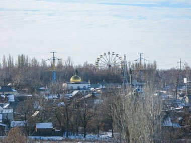 Konut binaları, karla kaplı tarlalar ve eğlence parkında ya da panayırda uzak bir dönme dolaba sahip kış manzarası. Ukrayna, Kostiantynivka, Ukrayna, 01-15-2013 hafif bulutlu gökyüzü.