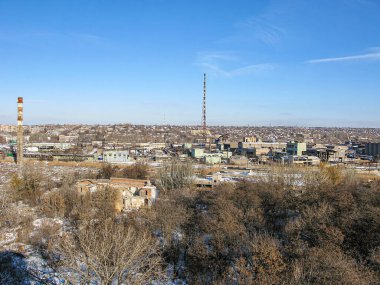 Yüksek bir yerden panoramik şehir manzarası, binaları, ağaçları, karı, elektrik hatlarını ve açık mavi gökyüzüne karşı faaliyetleri gösteriyor Kostiantynivka, Ukrayna, 01-15-2013