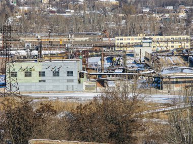 Görüntü, Kostiantynivka, Ukrayna, 01-15-2013 sahnesinde, kentsel bir bölgedeki diğer bina ve depolarla çevrili, birden fazla bölüm ve makineye sahip, karla kaplı büyük bir endüstriyel kompleksi gösteriyor.