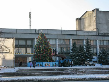 Bir kış sahnesinde süslü bir Noel ağacı, bir melek heykeli ve tiyatro sözcüğünün yer aldığı bir kamu binası yer alıyor. Kostiantynivka, Ukrayna, 01-15-2013