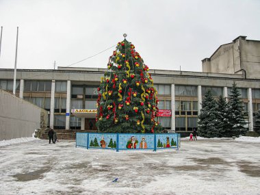 Bir eğitim kurumunun yanında, dışarıda duran bir Noel ağacı sahnesinde bir İsa 'nın Doğumu sahnesi ve uzaktaki insanlar, Ukrayna' daki Kostiantynivka, 01-15-2013 tarihli bir Kostiantynivka 'yı ima ederek yeri kaplıyor.