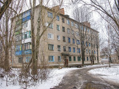 Görüntü, Orta veya Doğu Avrupa 'da daha soğuk aylarda Kostiantynivka, Ukrayna, 01-15-2013 döneminde tuğla işi, sayısız pencere, beyaz çerçeve ve mavi panjurlu çok katlı bir konut gösteriyor.