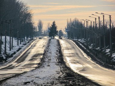 Kaldırımı ve demiryolunu ikiye bölen, sonbahar ya da kış arkaplanlarında çıplak ağaçlarla çevrili bir yol görüntüsü. Sahne yumuşak ışıklandırma koşullarıyla yıkanmış, poss Kostiantynivka, Ukrayna, 01-15-2013