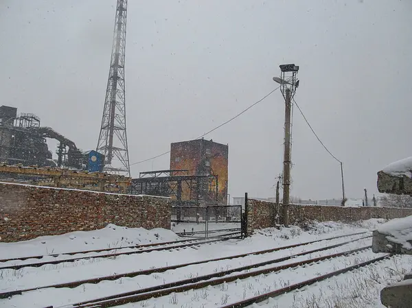 Terk edilmiş bir alanı, paslı kapısı, harap olmuş sanayi binası, bacası veya kulesi, kar yağışı, seyrek bitki örtüsü, sisli ufuk, kasvetli gökyüzü, saksı Kostiantynivka, Ukrayna, 01-15-2013