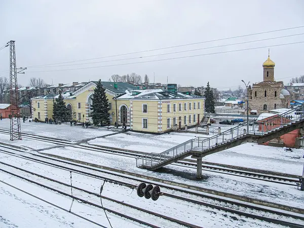 Bir demiryolu, paralel raylar, küçük bir platform ve aralarında önde gelen sarı bui Kostiantynivka, Ukrayna, 01-15-2013 'ün de yer aldığı mimari ayrıntılara sahip çok sayıda binanın yer aldığı karlı bir kış sahnesi.