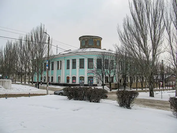Yapraksız ağaçlar ve çimlerle çevrili tarihi, karla kaplı bir binanın görüntüsü ve Kostiantynivka, Ukrayna 'da bir tabela, 01-15-2013