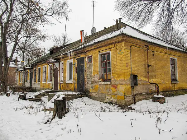 Çıplak ağaçlar ve bulutlu kışın ortasında karla kaplı eski bir binanın görüntüsü. Hiçbir insan faaliyeti görünmüyor. Yapının Kostiantynivka, Ukrayna, 01-15-2013