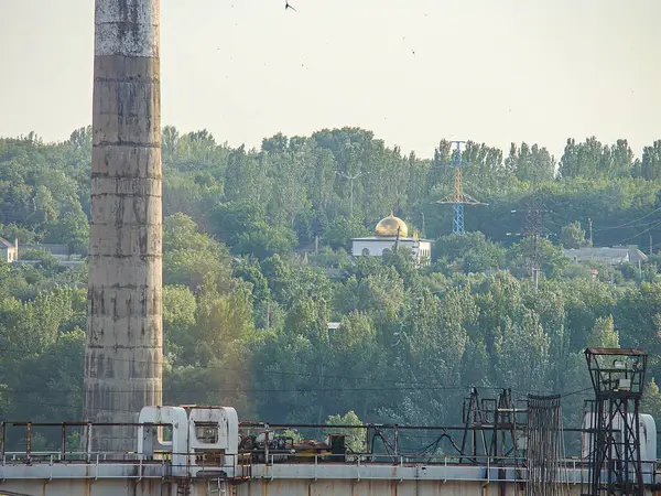 Yüksek bacalı, yemyeşil ağaçlarla çevrili bir sanayi santrali. Gökyüzü bulutlu. Görünürde Kostiantynivka, Ukrayna, 06-15-2013