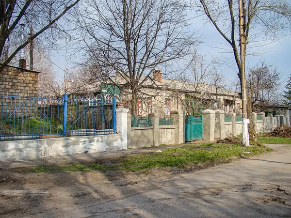 Görüntü, çıplak ağaçlarla kaplı asfalt bir caddede kırmızı çatılı bir binanın bulunduğu eski ve sessiz bir yerleşim alanını gösteriyor. Olay yerinde Kostiantynivka, Ukrayna, 01-15-2013