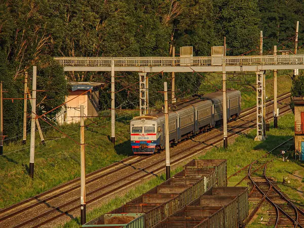 Kırsal bir demiryolu rayında hareket halindeki bir trenin bitişiğinde gable bir bina, elektrik kabloları ve arka planda ağaçlar var. Görüntü Kostiantynivka, Ukrayna 'da hareket bulanıklığı var, 06-15-2013