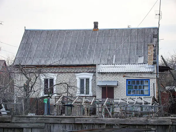 Yıpranmış, muhtemelen terk edilmiş iki katlı çatısı olan bir ev. Her katta üç pencere, alt katta mavi panjurlar ve Ukrayna, Kostiantynivka 'da küçük bir veranda var. 01-15-2013.