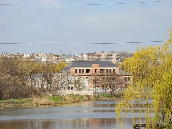 Geniş bir su kütlesi, bir bina, elektrik hatları ve bir ağaç ile sakin bir manzara görüntüsü sonbahar veya yaz sonu Kostiantynivka, Ukrayna, 01-15-2013