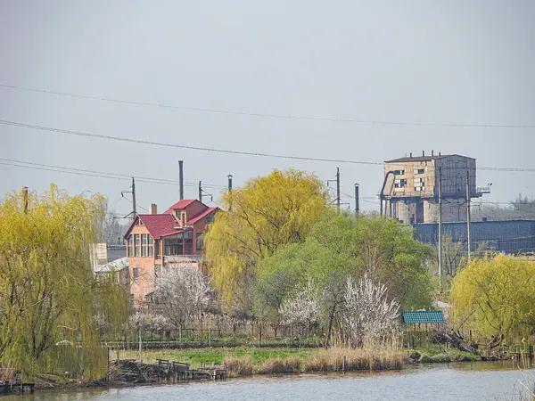 Sakin bir rıhtımda terk edilmiş bir sanayi tesisi. Çürüme belirtileri gösteriyor. Sakin su kütlesi açık mavi gökyüzünü sonbahar veya kış aylarında, Kostiantynivka, Ukrayna, 01-15-2013