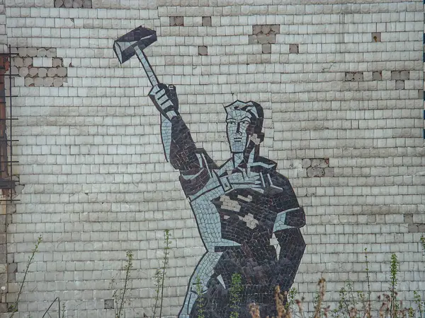 Görüntü, karo elementli merkezi bir figürün yer aldığı eski bir binanın üzerinde tek renkli bir duvar resmi gösteriyor. Şekil, kucaklayıcı veya Kostiantynivka, Ukrayna, 06-15-2013