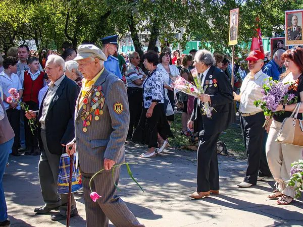 Açık havada düzenlenen bir etkinlikte, çeşitli katılımcılar ve takdir simgeleriyle üç katmanlı fotoğrafta yer alan yaşlı bir adam ödül veya ödül alırken, sahne Kostiantynivka, Ukrayna, 06-15-2013