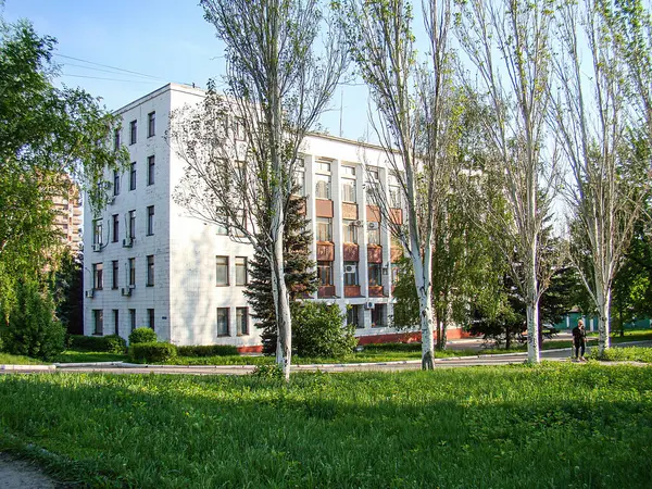 Görüntü, pencereleri, balkonları ve ısıtma sistemleri olan Avrupa tarzı çok katlı bir bina gösteriyor. Ön planda ağaçlar park gibi yeşil bir alan veya l Kostiantynivka, Ukrayna, 06-15-2013