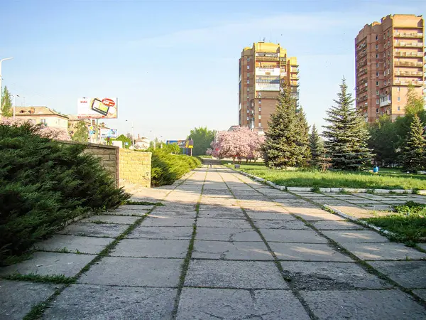 Asfalt yolu olan şehir parkı, yüksek binalar, çiçek açan pembe çiçekler, küçük çardak, açık mavi gökyüzü Kostiantynivka, Ukrayna, 06-15-2013