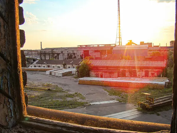 Görüntü, demir parmaklıklı pencerelerden geçen sanayi ortamının dinamik ve hızlandırılmış bir görüntüsünü gösteriyor. Sahne, Kostiantynivka, Ukrayna, 06-15-2013 tarihli geniş bir açık alan ve sandık yığınlarını gösteriyor.