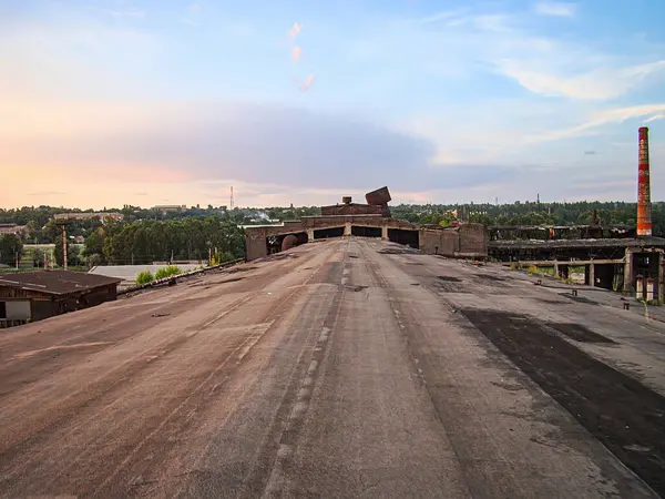Terk edilmiş, çürüyen bir sanayi binasının bir kısmı köprüye bağlanmış durumda. Yapı, Kostiantynivka, Ukrayna, 06-15-2013 etrafındaki hava durumu ve hasar belirtilerini gösteriyor.
