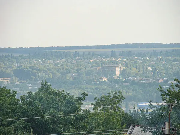 Panoramik şehir manzarası yüksek perspektiften ön planda ağaçlar, elektrik direkleri çeşitli boyutlarda orta saha binaları yerleşim ve ticari Kostiantynivka, Ukrayna, 06-15-2013