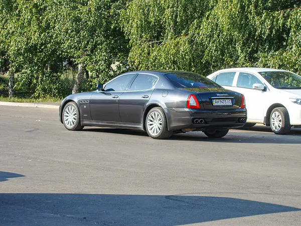 Koyu renkli, muhtemelen siyah ya da koyu mavi renkli bir araba. Açık hava parkında park halinde. Görüntü kamera açısı nedeniyle biraz bozuk ve Kostiantynivka, Ukrayna, 06-15-2013