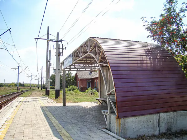 Kavisli metal sığınaklı tren istasyonu platformu, sarı güvenlik işaretleri, işaretli direk, kırsal-kırsal arka plan, boş platform, gündüz vakti Kostiantynivka, Ukrayna, 06-15-2013