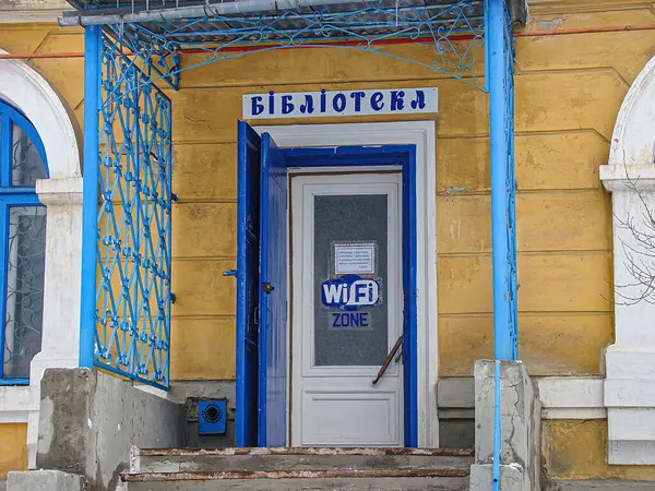 Beyaz kapılı, iki küçük pencere ve Kiril alfabesiyle çevrili eski bir Avrupa binasının görüntüsü Wi-Fi erişilebilirliği Kostiantynivka, Ukrayna, 01-15-2013