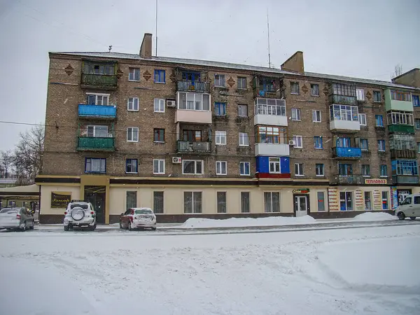 Görüntü, balkonları, dağınık karları ve Kostiantynivka, Ukrayna 'da sessiz bir şehir merkezinde restoranı olan çok katlı bir konut binasını gösteriyor. 01-15-2013