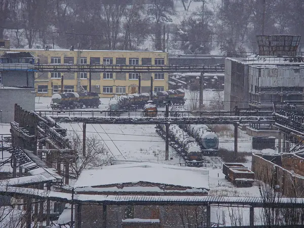 Demiryolu rayları, binalar, konteynırlar ve tankların bulunduğu karlı sanayi manzarası Gökyüzü, durgunluk, boşluk, etkinlik veya insan varlığı yok, Candi Kostiantynivka, Ukrayna, 01-15-2013