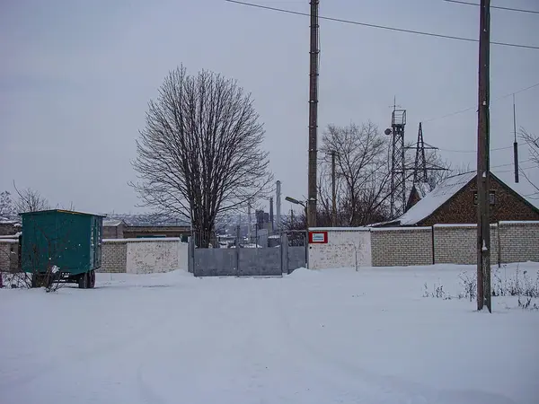 Görüntü, büyük bir metal yapısı, muhtemelen bir trafo veya elektrik tesisatı olan, derin kar ve küçük kırmızı bir Kostiantynivka, Ukrayna, 01-15-2013 ile çevrili karlı bir manzara gösteriyor.
