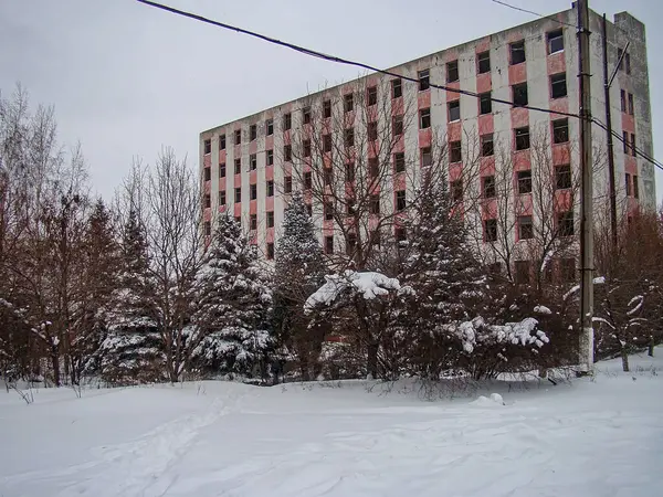 Görüntü, üç katlı, üniforma pencereli ve sakin bir kış manzaralı, karla kaplı beton bir binayı tasvir ediyor: Kostiantynivka, Ukrayna, 01-15-2013