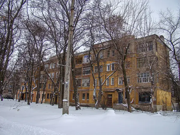 Kışın, çıplak ağaçlar ve bulutlu gökyüzü Kostiantynivka, Ukrayna, 01-15-2013 ile karla kaplı çok katlı meskun bir bina.