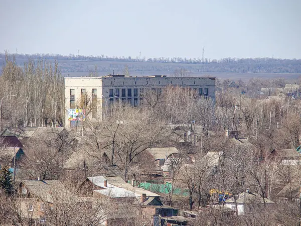 Soğuk iklim manzaralı küçük bir kasaba ya da yerleşim yerinin perdeli çatı evleri, daha büyük kurumsal okul binası, bulutlu gökyüzü, çim Kostiantynivka, Ukrayna, 06-15-2013