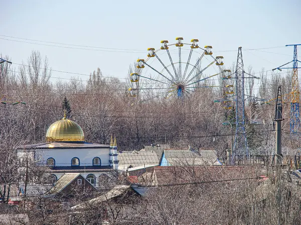 Önde gelen altın camii ve operasyonel dönme dolabı, bulutlu gökyüzü, çeşitli şehir manzarası, çıplak ağaçlar, elektrik hatları, ind Kostiantynivka, Ukrayna, 06-15-2013