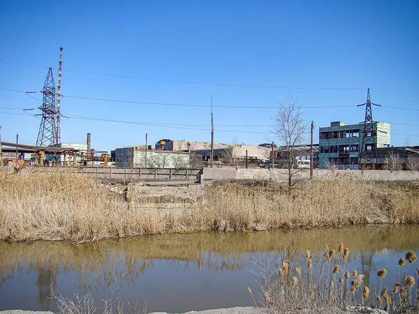 Terk edilmiş inşaat yapıları ve fabrikalarla çevrili sakin bir su kütlesi, muhtemelen bir kanal veya nehir olan sanayi bölgesi, uzun bacalar Kostiantynivka, Ukrayna, 06-15-2013