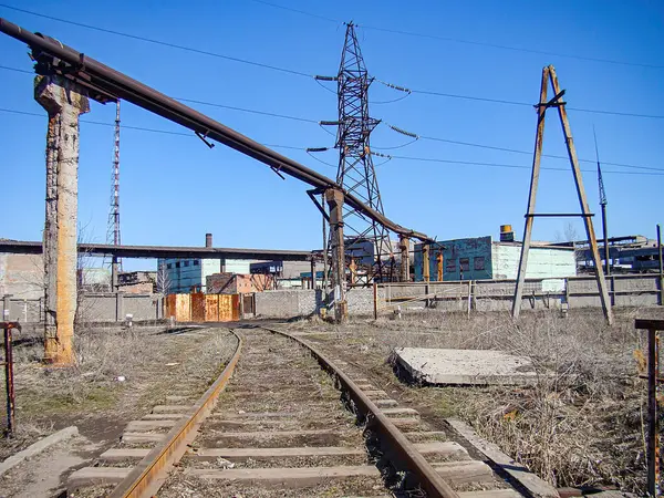Terk edilmiş mavi gökyüzü altında terk edilmiş bir sanayi bölgesi, üzerinde aşırı gelişmiş paslı izler ve bitkisel hayattaki Kostiantynivka, Ukrayna, 06-15-2013