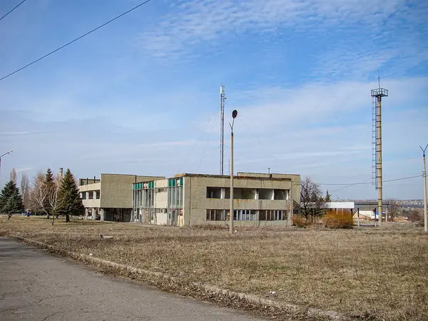 Çimenli, düz bir alanda iki katlı bir bina, markalaşma veya belirgin özellikleri yok, sol tarafta elektrik direkleri, ve arka planda Kostiantynivka, Ukrayna, 01-15-2013