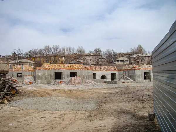 Görüntü, tamamlanmamış yapıları, açıkta kalan beton duvarları, tesisat boruları, bitki örtüsü, yakındaki bina, bulutlu gökyüzü, çıplak toprak, devam eden Kostiantynivka, Ukrayna, 01-15-2013