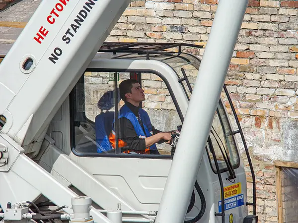 Görüntü, bir inşaat işçisinin turuncu güvenlik yeleği giydiğini gösteriyor, tehlikeli bir bölgede bir uyarı işareti ile belirtilen Kostiantynivka, Ukrayna, 01-15-2013