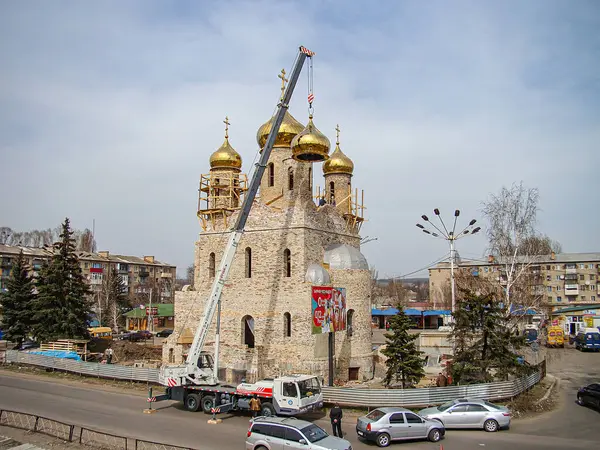 Kentsel alanda birden fazla kubbe ve minarenin yer aldığı bir cami, bir vinç, inşaat bariyeri, ağaçlar ve Kostiantynivka, Ukrayna, 01-15-2013