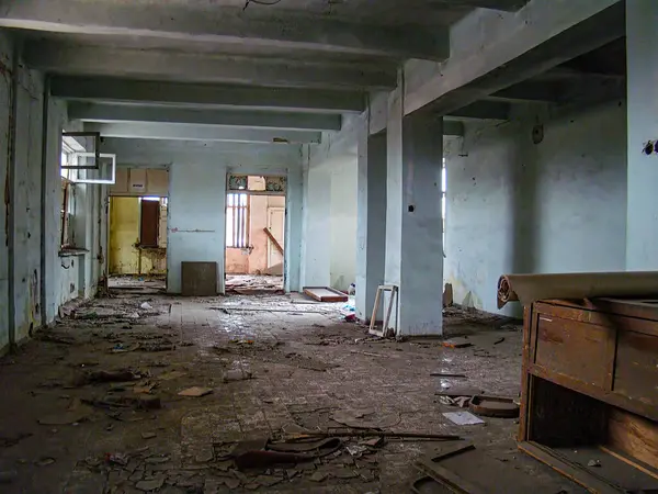 Mavi duvarları, enkazı, kırık mobilyaları ve büyük bir tahta parçası olan harap bir iç mekan. Tavan kirişleri ve açıkta kalan yalıtımı gösteriyor. Doğal I Kostiantynivka, Ukrayna, 01-15-2013