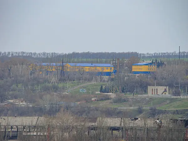 Önplanda büyük, muhtemelen sanayi tipi sarı ve mavi çatılı kırsal alan manzarası alçak tepelere veya dağlara geçiş sahneleri, Kostiantynivka, Ukrayna, 01-15-2013