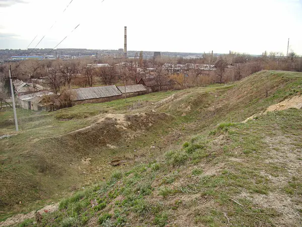 Dalgalanık arazi manzarası, küçük tepeler, kuru toprak, çimen, bitki örtüsü, muhtemelen bir ev, ağaçlar, Kostiantynivka, Ukrayna 'da sanayi bölgesi, 01-15-2013