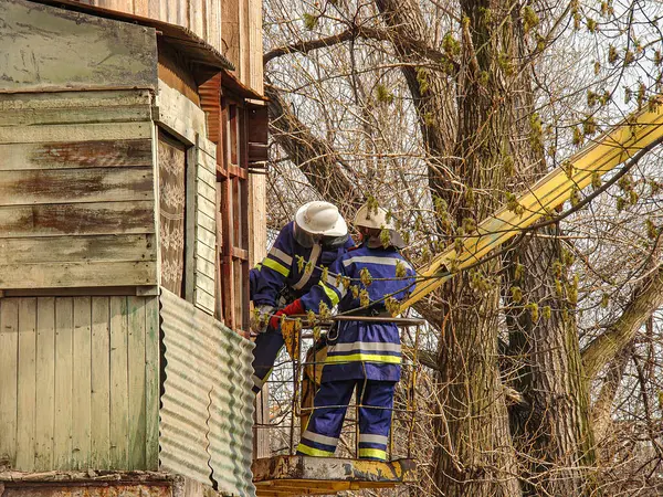 Koruyucu giysili iki kişi, muhtemelen sonbahar ya da kış aylarında bir yapının yakınında bir açık hava etkinliğinde bulunuyorlar. Kostiantynivka, Ukrayna, 01-15-2013, tanımlanamayan görevlerine odaklanıyorlar.